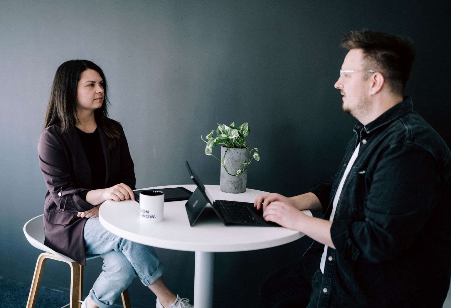 Ein Mann und eine Frau sitzen an einem Tisch mit einem Laptop und diskutieren über digitale Strategien.