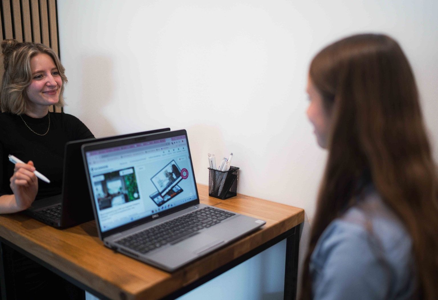 Zwei Frauen sitzen an einem Tisch und arbeiten gemeinsam an einem Laptop.